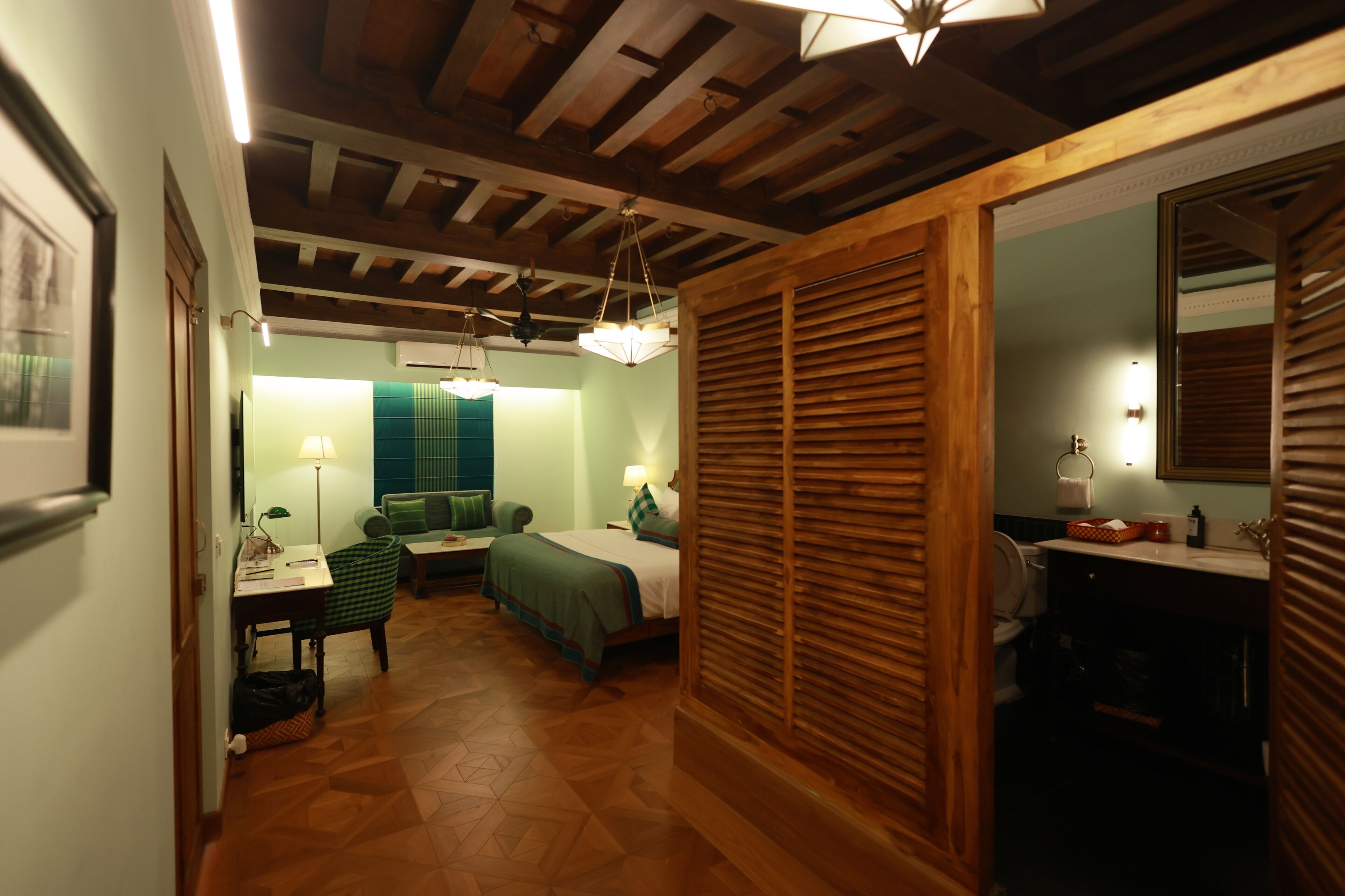Una habitación con cama, escritorio, silla, lámpara y espejo.