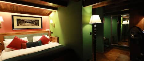 A hotel room with a bed, a nightstand, a lamp, a framed picture on the wall, and a mirror.