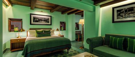 A room with a bed, a sofa, a lamp, and a framed picture on the wall.