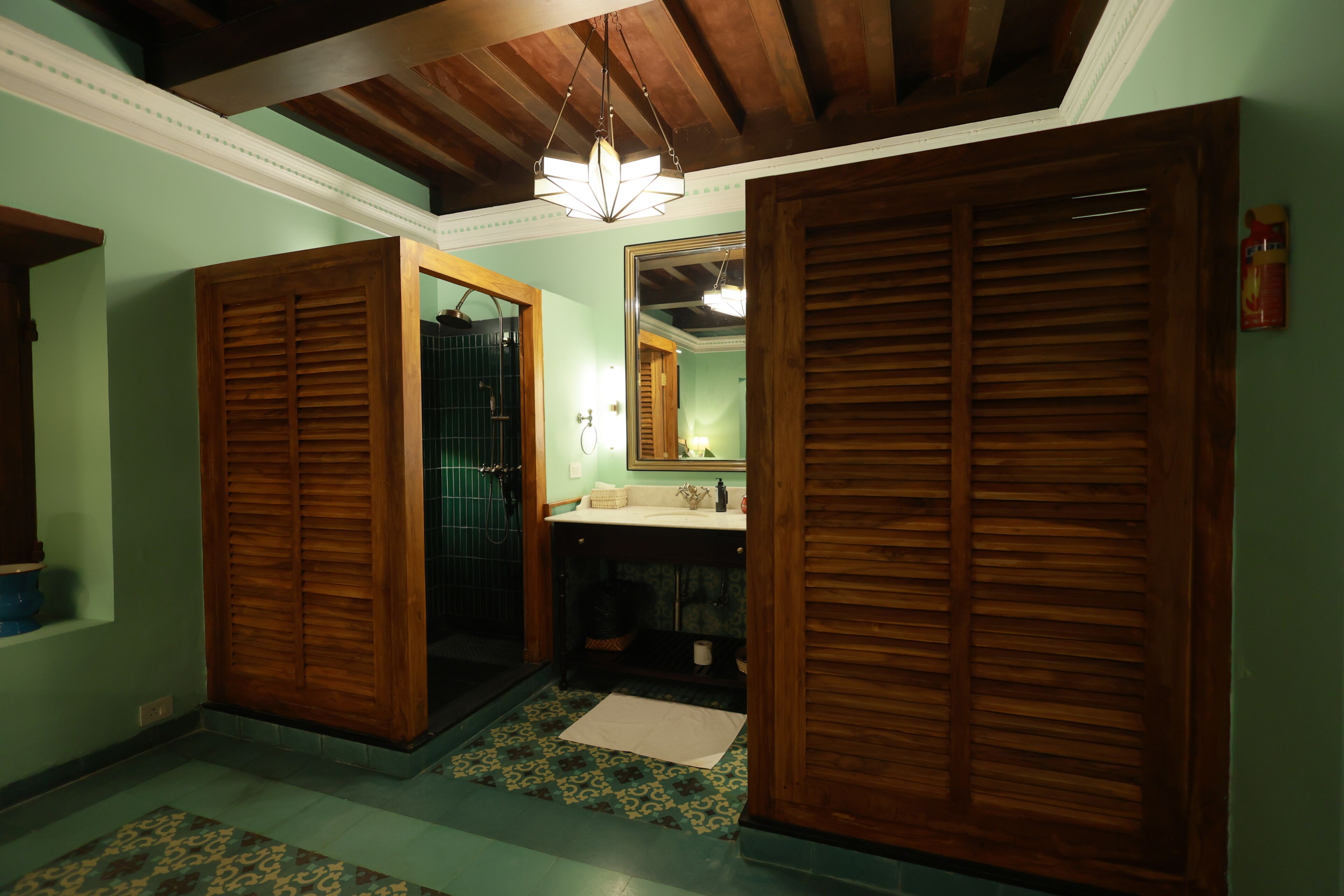 Una habitación con puertas de madera, un lavabo, un espejo y un suelo con estampado.