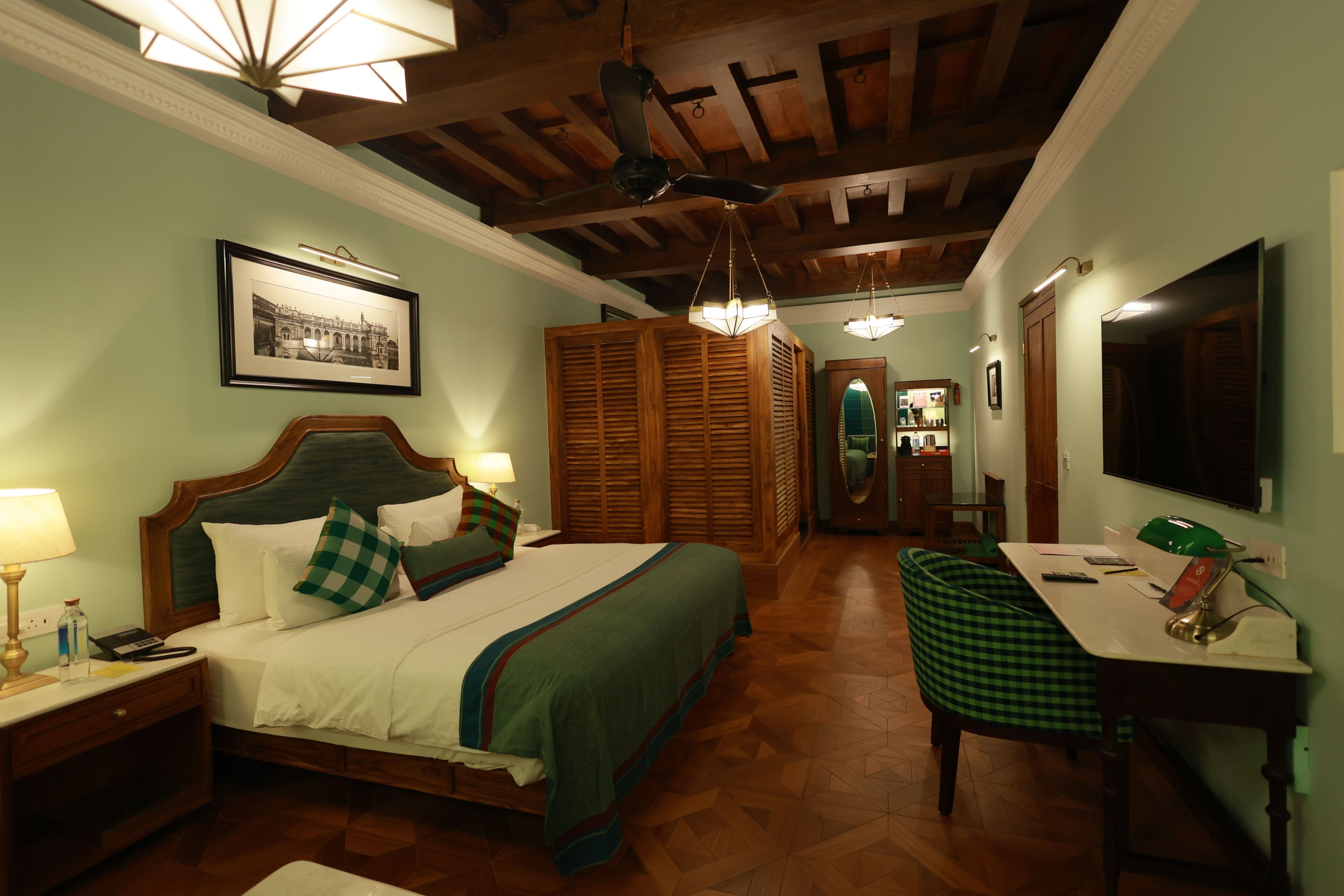A hotel room with a bed, bedside table, lamp, and a desk with a chair.