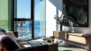 Ein modernes Wohnzimmer mit großen Fenstern, einem Sofa, einem Couchtisch und einem Gemälde.