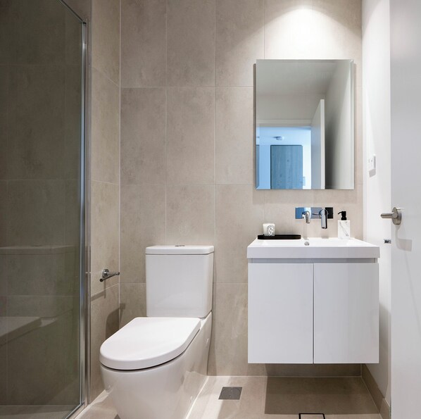 A modern bathroom with a toilet, sink, and mirror.