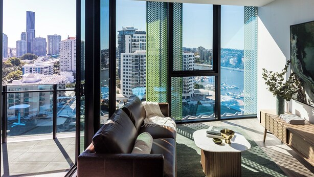 Ein modernes Wohnzimmer mit Blick auf die Stadt, großen Fenstern und einer gemütlichen Sitzecke.