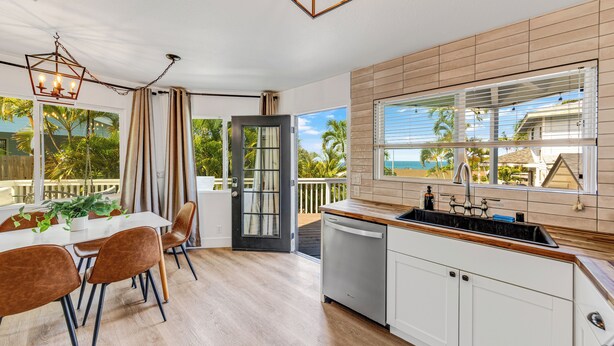 A modern kitchen with a wooden countertop, white cabinets, and a view of the ocean through large windows.