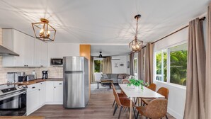 A modern kitchen with white cabinets, stainless steel appliances, and a dining area with a white table and brown chairs.