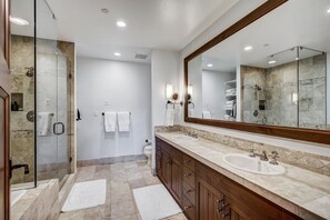 Features a spacious layout with a glass-enclosed shower area, dual sinks, and ample storage.