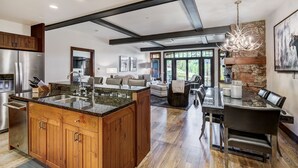 A spacious kitchen with a large island, wooden cabinets, and a stone accent wall. - Remodeled 3br Condo In Bachelor Gulch - Ski In/out 3 Bedroom Condo (Avon)