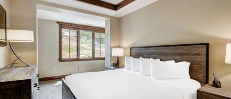 Un dormitorio con una cama grande, cabecera de madera y ventilador de techo. Hay una ventana que ofrece luz natural y vistas al exterior.