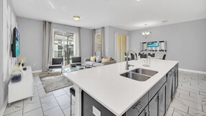 A modern kitchen with a large island, built-in appliances, and a dining area with a sofa and chairs. - 1569plunker 4 Bedroom Townhouse (Davenport)