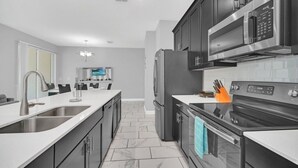 A modern kitchen with dark cabinetry, stainless steel appliances, and a tiled backsplash. - 1569plunker 4 Bedroom Townhouse (Davenport)