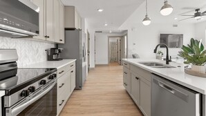 Eine moderne Küche mit Edelstahlgeräten, einer zentralen Kochinsel mit Spüle und hellem Holzboden.