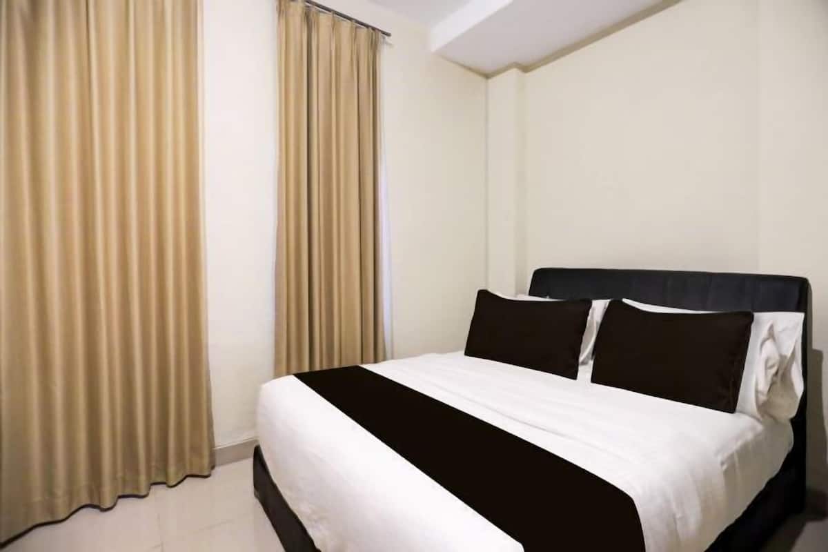 Hotellihuone, jossa on sänky, verhot ja sängynpääty.