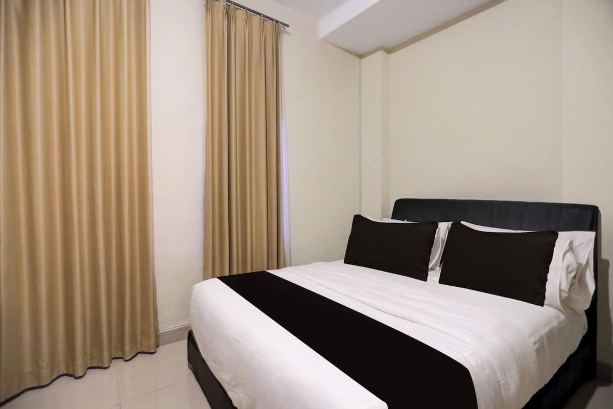 Hotellihuone, jossa on sänky, verhot ja sängynpääty.