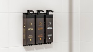 Un ensemble de distributeurs de produits de toilette noirs, fixés sur un mur recouvert de carreaux blancs.