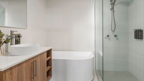 Une salle de bain moderne avec une baignoire sur pieds, une douche à parois de verre et un meuble-lavabo avec un évier et un miroir.