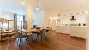 A modern kitchen with a central island, wooden flooring, and pendant lighting. - Solemar Sicilia - Al Kasar (Palermo)