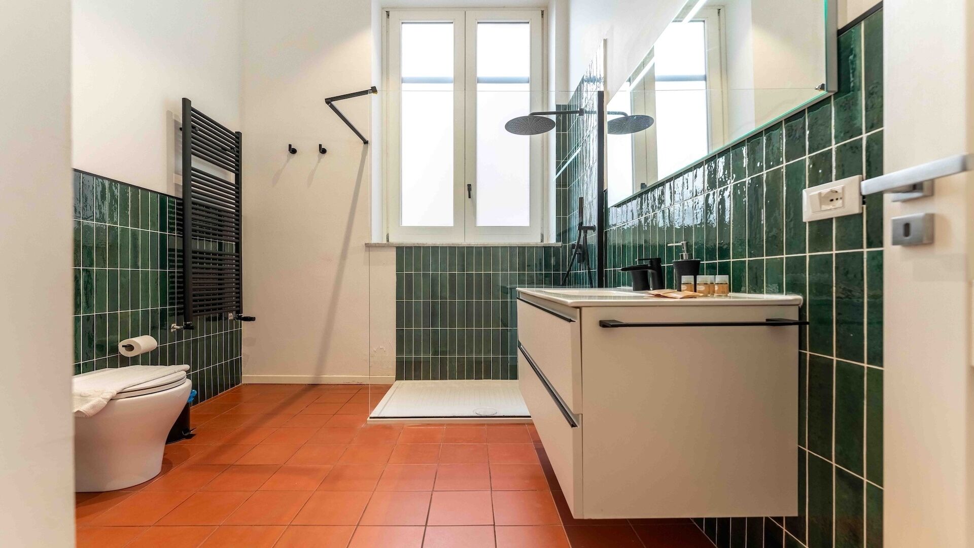 Une salle de bain avec des toilettes, un lavabo, un miroir et une fenêtre.