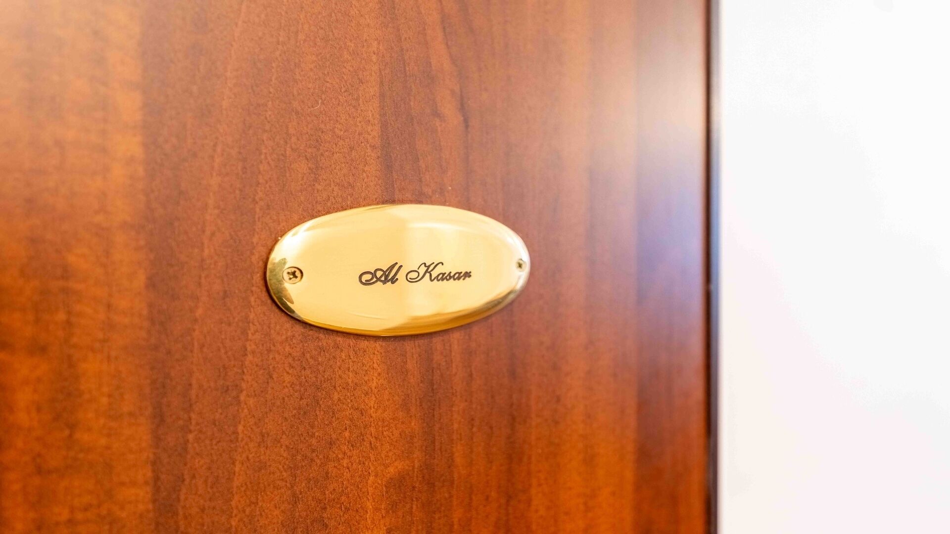 A wooden door with a brass nameplate that reads 'Al Kasar'.