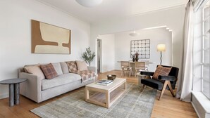 Un salon moderne avec un canapé, une table basse et un coin repas comprenant des chaises et une lampe.