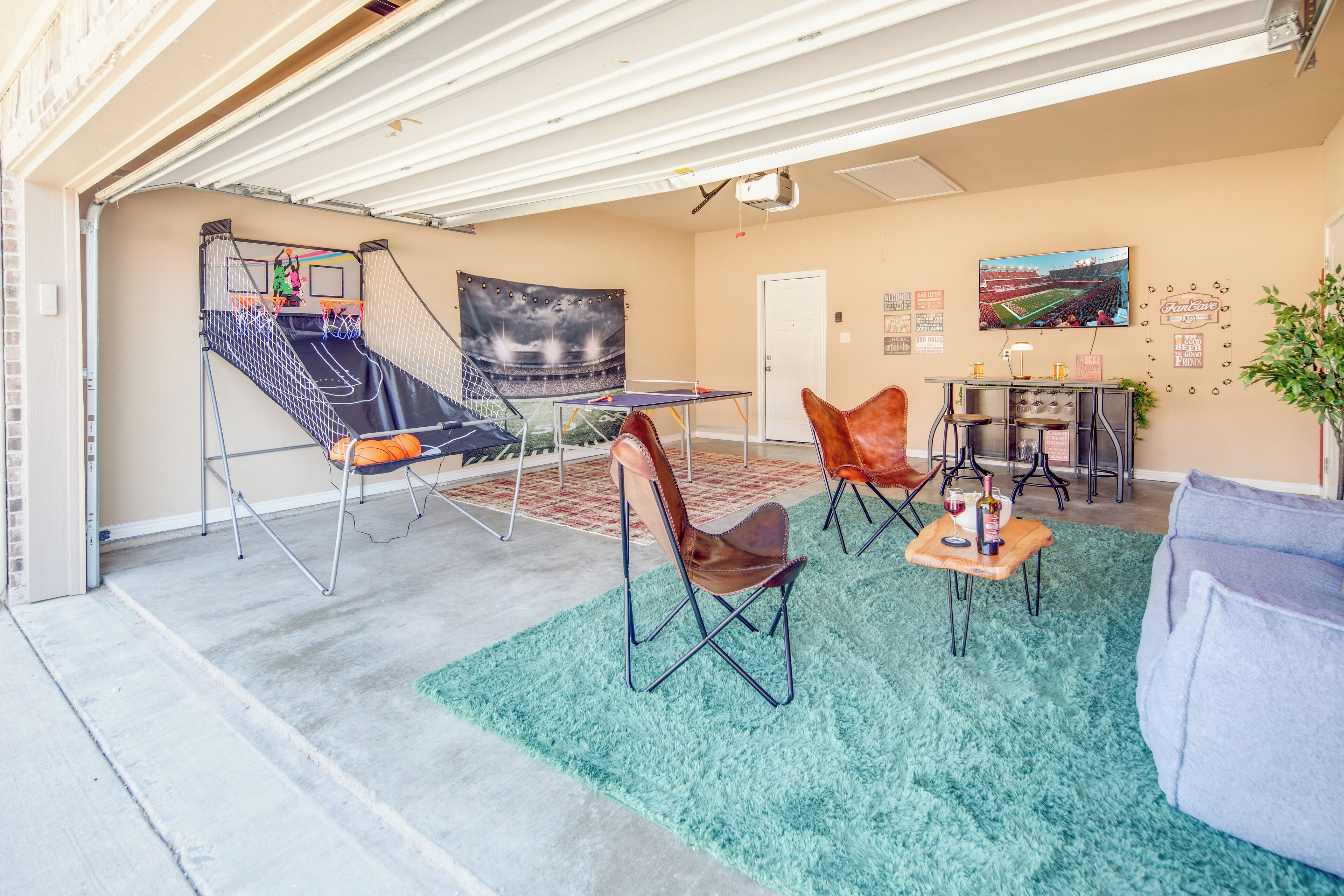 A garage with a trampoline, seating area, and a TV mounted on the wall.