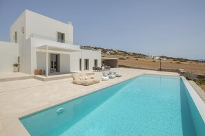 Una casa moderna con piscina, mobiliario exterior y vistas al paisaje.