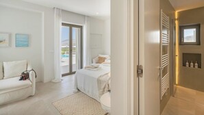 Habitació d'hotel moderna amb llit, sofà, bany amb dutxa i vistes cap a l'exterior.