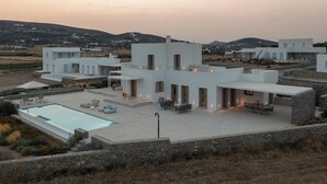 Una vila moderna amb piscina, mobiliari exterior i vista al paisatge circumdant.