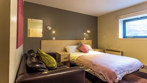 A hotel room with a bed, a nightstand, a chair, a mirror, and a window. - Student Only Pittodrie Street (Aberdeen)