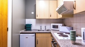 A compact kitchen with a refrigerator, microwave, stove, and sink. - Student Only Pittodrie Street (Aberdeen)
