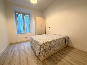 Une chambre à coucher avec un lit, une armoire, une fenêtre et un luminaire.
