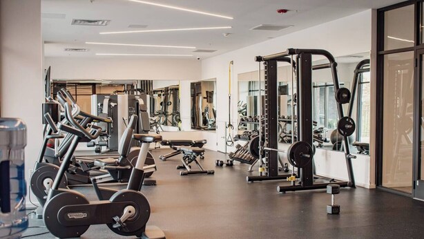 Een moderne sportschool met diverse fitnessapparaten, waaronder loopbanden, krachttoestellen en losse gewichten.