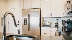 Een moderne keuken met roestvrijstalen apparatuur, een ingebouwde waterdispenser, een broodrooster en een koffiezetapparaat.