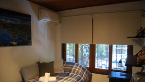 A bedroom with a bed, pillows, a map on the wall, an air conditioner, a window, and a desk with a lamp. - Cosmo Mendoza Suites (Mendoza)