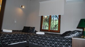 A bedroom with two beds, a window with a view of greenery, an air conditioner, and a bedside lamp. - Cosmo Mendoza Suites (Mendoza)