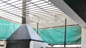 An outdoor patio with a built-in pizza oven, a small table with glasses and a bottle, and a potted plant. - Cosmo Mendoza Suites (Mendoza)
