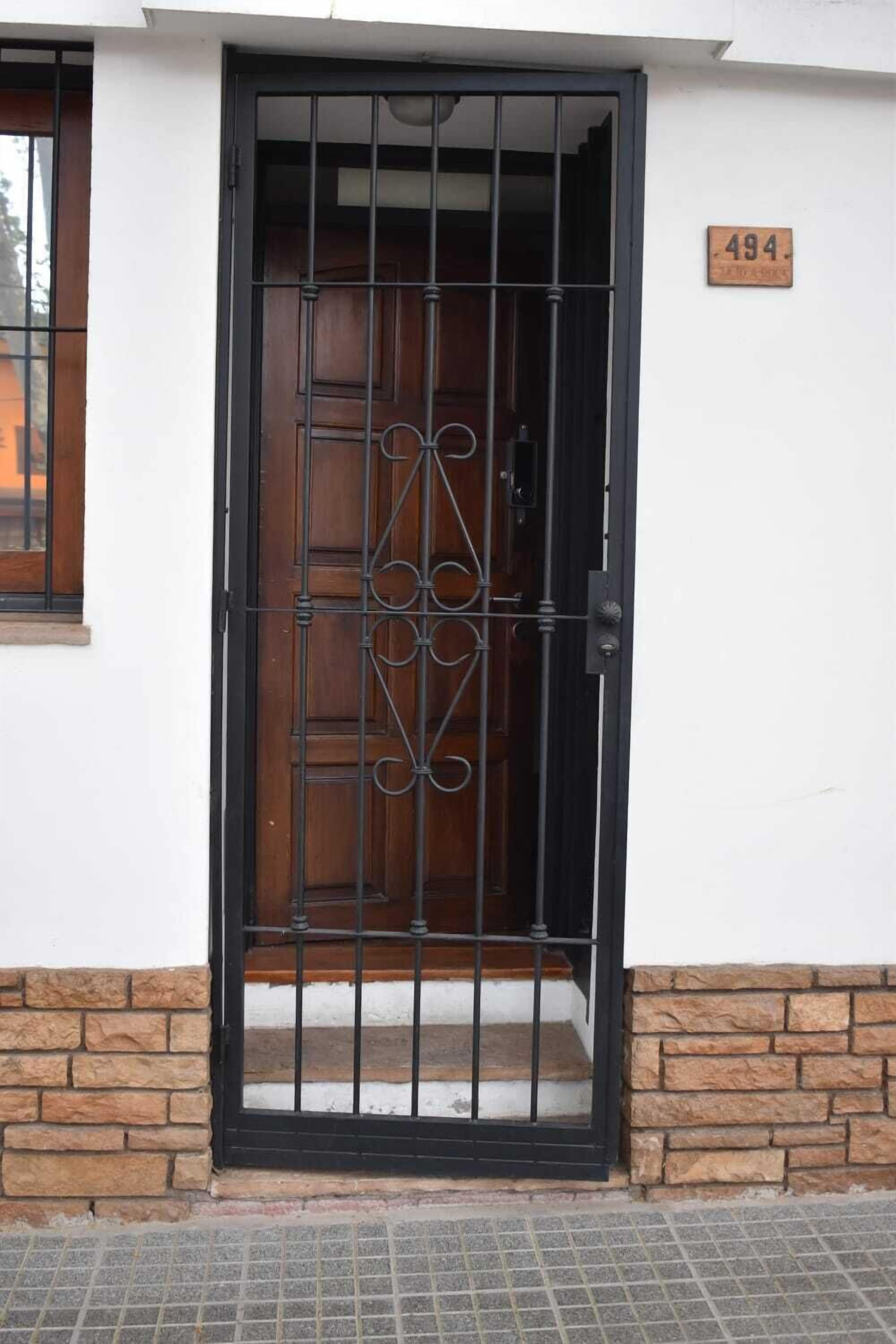 A wooden door with a metal gate, a stone base, and a house number 494.