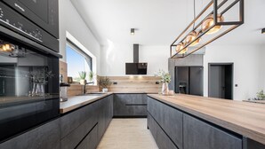 Een moderne keuken met donkere kastjes, een houten aanrechtblad en een centraal eiland.