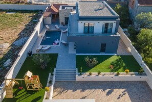 Uma casa moderna com piscina, um pequeno jardim e área de lazer.