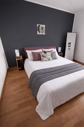 A modern bedroom with a large bed, dark walls, and a wooden floor. - VM Ravenna Luxury Apartment. 2 bedrooms in the heart of the historic center. (Ravenna)