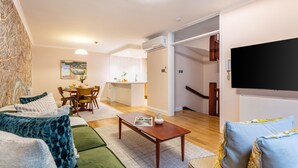 A modern living room with a sofa, a coffee table, and a TV. There is a dining area with a table and chairs. - Spacious 2BR House by Madame Tussauds  (London)