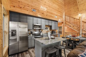 A modern kitchen with stainless steel appliances, grey cabinets, and a central island with bar stools. - Wears Valley Close to Pigeon Forge*Private Pool*Game Room (SEVIERVILLE)