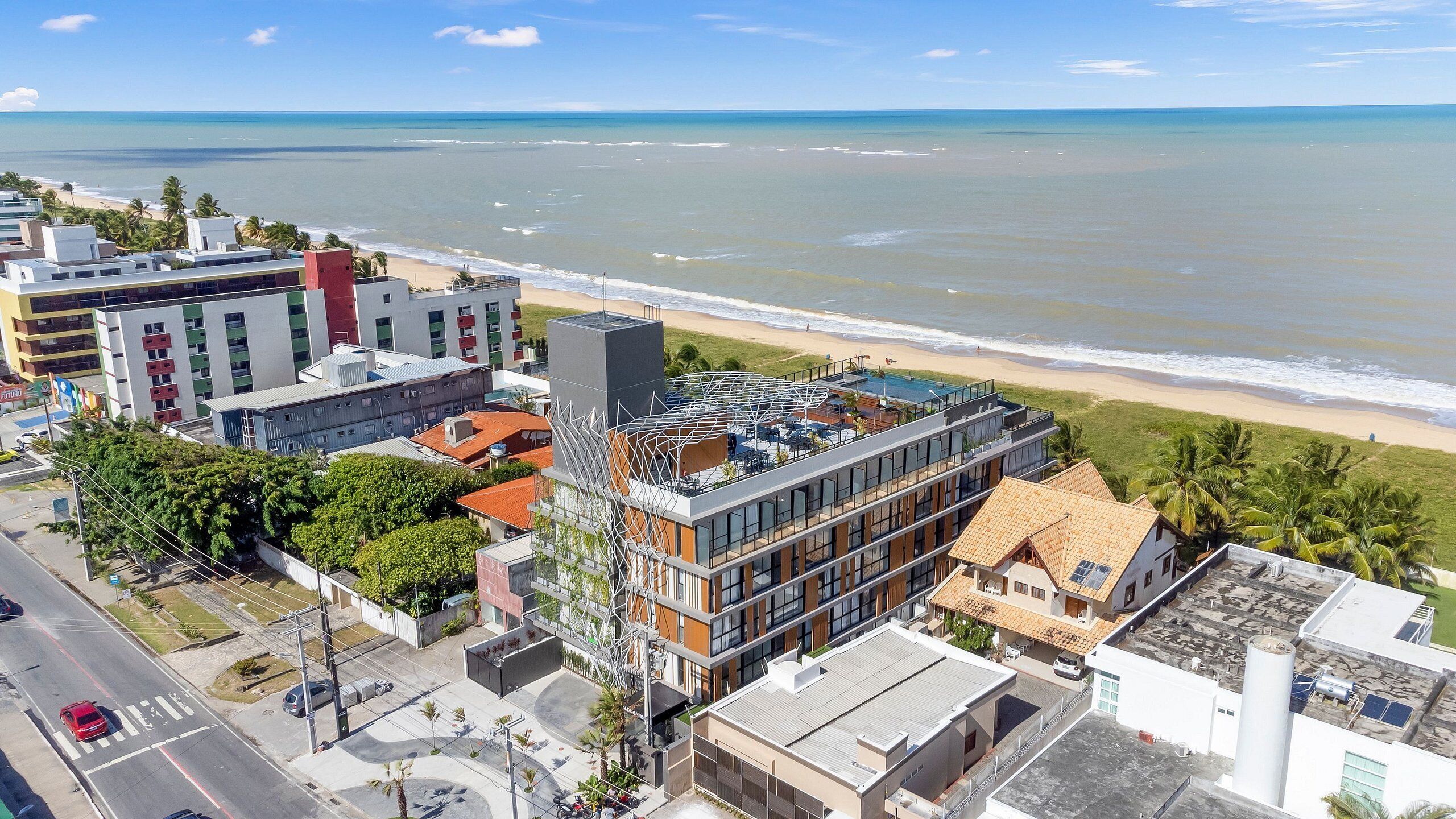 An aerial view of a coastal urban area with modern buildings, a beach, and a clear sky.