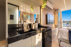 Moderni hotellihuone, jossa on keittotila, suuri sänky ja näkymä kaupunkiin.