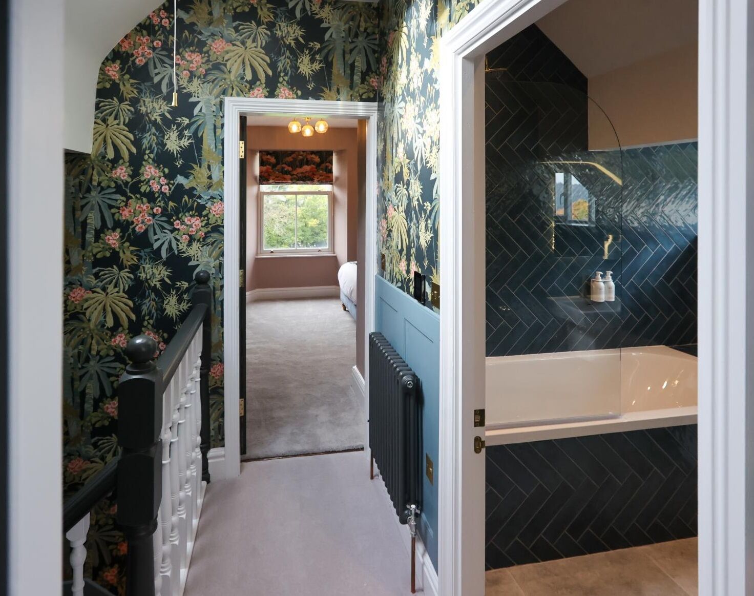 A hallway leading to a bedroom with floral wallpaper, a radiator, and a view of the outdoors.