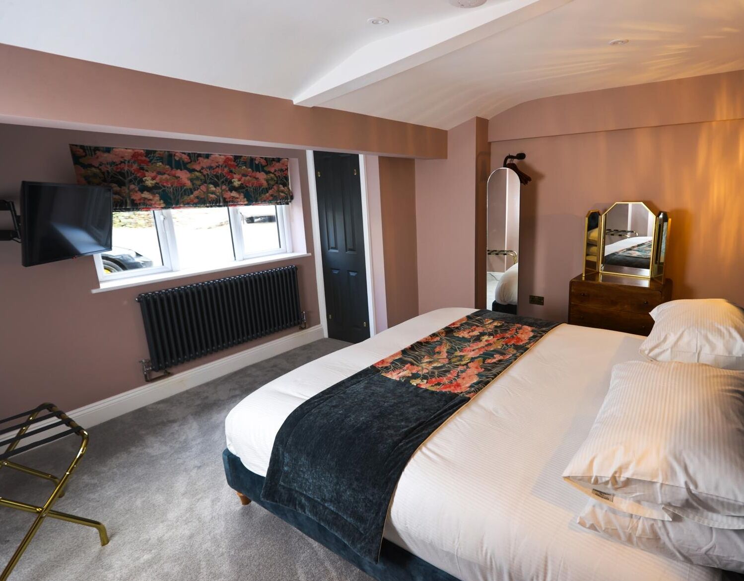 Une chambre à coucher comprenant un lit, un radiateur, une fenêtre avec des rideaux, un miroir et un porte-serviettes mural.
