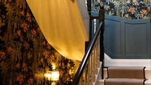 A staircase with a floral wallpaper, a white drape, and a wall-mounted light fixture. - Fair Rigg by Cradel Haus (Windermere)
