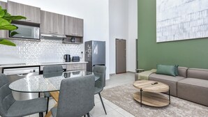 Una cocina moderna con una mesa de comedor de vidrio, sillas grises y un refrigerador gris.