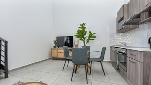 Una cocina compacta con una mesa de comedor y sillas, un televisor y un microondas.