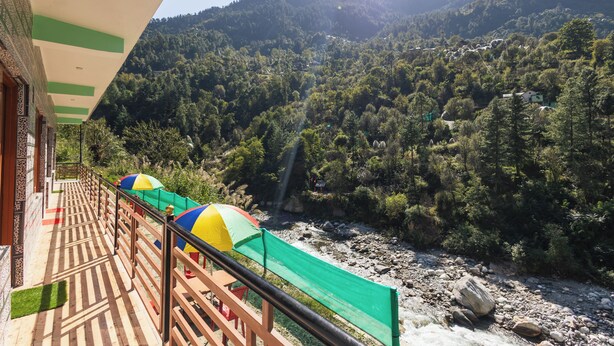 Un balcon avec vue sur une rivière et des montagnes boisées.